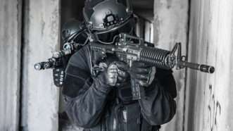 Police officers in SWAT gear holding automatic weapons, move through a building as if conducting a raid. | Oleg Zabielin | Dreamstime.com