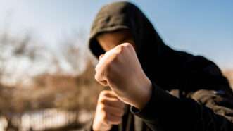 A man in a hoodie holds up his fists, as if ready for a fight. | Alpar Benedek | Dreamstime.com