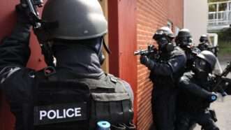 A SWAT team stands outside a building, preparing to enter | ID 18800265 | Swat Team ©  Martin Brayley | Dreamstime.com