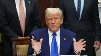 President Donald Trump addresses reporters while sitting at a desk to sign an executive order. | Chris Kleponis - via CNP/Polaris/Newscom