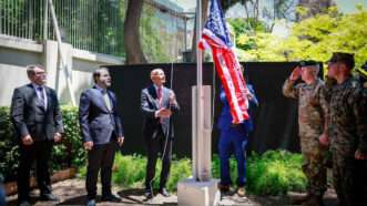 Syrian Foreign Minister Assaad al-Shibani looks on as U.S. Special Envoy Thomas Barrack raises the flag of the United States at the U.S. ambassador's residence in Damascus, Syria. May 29, 2025. | Syrian Arab News Agency (SANA)/UPI/Newscom