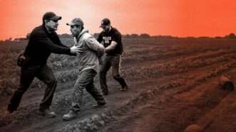 A black and white image of two ICE agents taking a farm worker into custody, a red-tinted field is in the background | Illustration: Eddie Marshall | Chat GPT