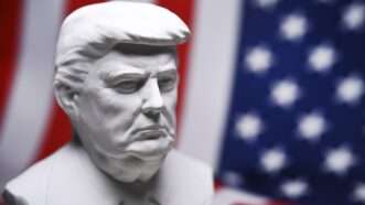 A marble-like bust of President Donald Trump, against an American flag in the background. | imageBROKER/Christian Ohde/Newscom