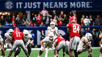 A presnap photo of a football game between Texas and Georgia, with Texas in their white jerseys and Georgia in their red ones. An SEC banner looms in the background with a slogan in all caps: "IT JUST MEANS MORE." | Rich von Biberstein/Icon Sportswire DKB/Rich von Biberstein/Icon Sportswire/Newscom