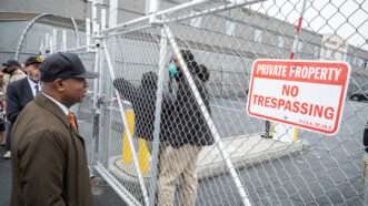 Newark Mayor Ras Baraka stands outside the front gate of Delaney Hall Detention Facility, The gate is closed, with two ICE agents standing on the other side, and a "Private Property No Trespassing" sign. | Brian Branch Price/ZUMAPRESS/Newscom