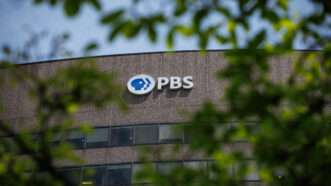 A picture of the PBS logo on the side of a building, as seen through tree branches | Samuel Corum/Sipa USA/Newscom