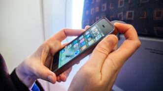 Close-up of a woman's hands as she turns off an iPhone, sitting in an airplane seat. | Ifeelstock | Dreamstime.com