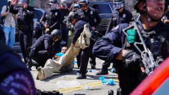 Armed law enforcement agents detain a man on the ground | Brandon Pollard/ZUMAPRESS/Newscom