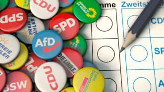 A German election ballot and pen, next to a pile of campaign pins with German political parties. AfD is in the middle. | Kontakt5956 | Dreamstime.com