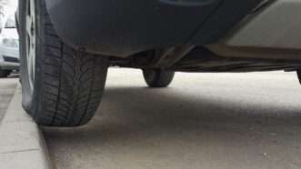 Close up on a parked car's tire, slightly suspended up on the curb. | Ognianmedarov | Dreamstime.com