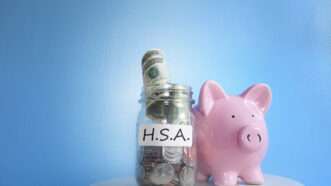 A piggy bank next to a jar of cash with a label that says "H.S.A." | Zimmytws | Dreamstime.com