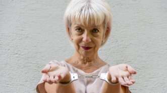 An elderly white woman with blonde hair is handcuffed. She holds her hands out with palms up. | Lepasik | Dreamstime.com