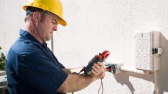 An electrician checks the voltage on an outdoor receptacle near a junction box. | Brian T. Young | Dreamstime.com