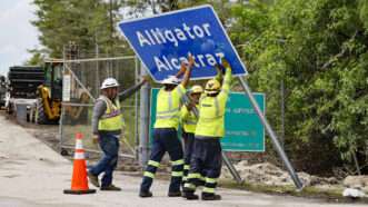 Workers raise a road sign that reads 'Alligator Alcatraz' | Al Diaz/TNS/Newscom