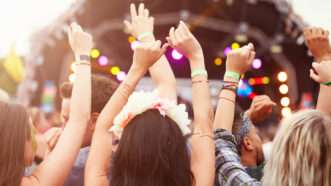 The crowd at a music festival, with concertgoers holding their hands in the air. | Monkey Business Images | Dreamstime.com