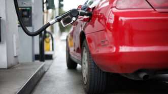 A red car sits at a gas station fuel pump with the nozzle inserted. | Konstantin Sutyagin | Dreamstime.com