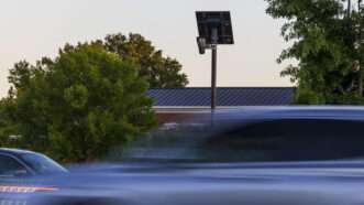 Traffic drives by an automated license plate reader (ALPR) mounted high on a roadside pole. | Kendall Warner/TNS/Newscom