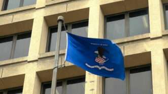 A flag with the Department of Justice logo flaps in the breeze in front of the FBI Building in Washington, D.C. | Christopher Bellette | Dreamstime.com