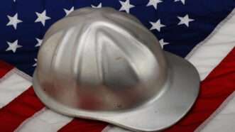 A silver hard hat for construction, sitting on an American flag. | W.scott Mcgill | Dreamstime.com