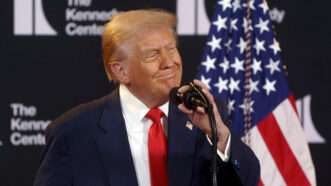 Donald Trump speaks into a microphone with an American flag and The Kennedy Center logo behind him | Will Oliver - Pool via CNP