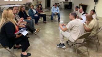 A group of people sitting in a circle of folding chairs; some of them are wearing inmate uniforms | Photo: Comisión de Desarrollo Cooperativo