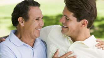 Two men hug in a public park. | Monkey Business Images | Dreamstime.com