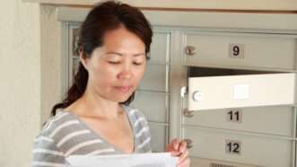 A woman checks the mail from her mailbox in an apartment building. | Cupertino10 | Dreamstime.com