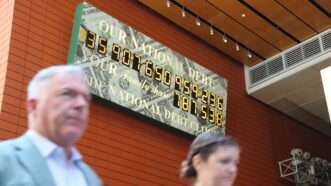 Pedestrians walk past the National Debt Clock in New York | Liu Yanan / Xinhua News Agency/Newscom