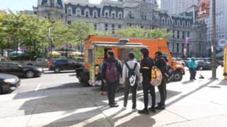 People line up to order from a food truck in front of Philadelphia City Hall. | Alan Budman | Dreamstime.com