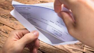 A man's hands open an envelope with a paycheck inside. | Andrey Popov | Dreamstime.com