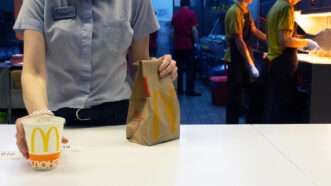 An employee serves a drink and a paper bag on a McDonald's counter | Photo: Vladimir Zuev/Alamy
