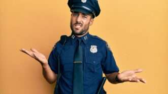 A young male police officer shrugs, with a confused expression on his face. | Aaron Amat | Dreamstime.com