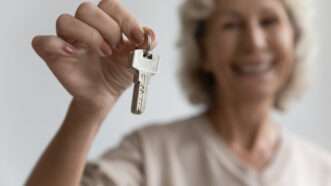 An older woman holds up a set of keys. | Fizkes | Dreamstime.com