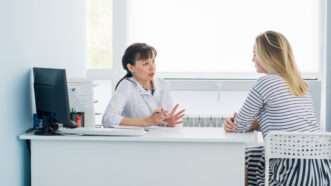 A doctor in her office speaks with a woman during a consultation. | Roman Kosolapov | Dreamstime.com