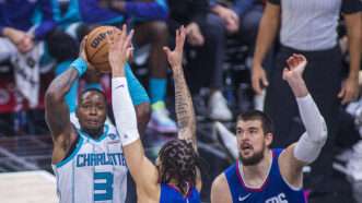 Terry Rozier, in a white Charlotte Hornets jersey, jumping up to take a basketball shot while defended by two players in blue Los Angeles Clippers jerseys. | Ariana Ruiz/ZUMAPRESS/Newscom