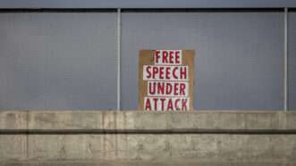 A protest sign saying "free speech under attack" sits above a highway overpass | ID <a href="https://www.dreamstime.com/political-protest-sign-stating-free-speech-under-attack-freeway-overpass-red-letters-image318434433">318434433</a> | <a href="https://www.dreamstime.com/photos-images/free-speech.html">Free Speech</a> ©  <a href="https://www.dreamstime.com/frank284_info">Frank Armstrong</a> | <a href="https://www.dreamstime.com/stock-photos">Dreamstime.com</a>