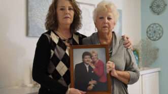 Paul John Bojerski's wife, Gayle Bojerski, and her daughter hold a photo of Paul and Gayle. | Ricardo Ramirez Buxeda/TNS/Newscom