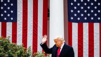 President Trump waving at the White House with American flags in the background | Samuel Corum/Sipa USA/Newscom