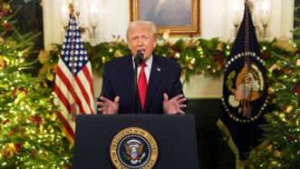Donald Trump standing in front of a lectern with Christmas decorations behind him | Doug Mills/The New York Times/UPI/Newscom