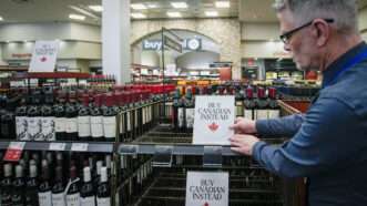 A man places a sign on a liquor store shelf that says 'buy Candian instead' | Liang Sen / Xinhua News Agency/Newscom