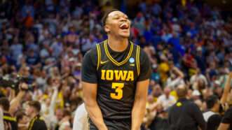 Iowa Hawkeyes forward Cam Manyawu celebrates on a basketball court, with a crowd of fans behind him. | Photo: Jefferee Woo/ZUMA Press/Newscom