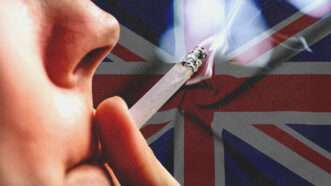Someone holds a lit cigarette to their lips with the U.K. flag in the background | Envato