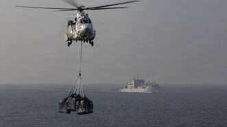A Eurocopter AS565 Panther helicopter transports cargo to the flight deck of Nimitz-class aircraft carrier USS Abraham Lincoln (CVN 72) during a replenishment-at-sea with Lewis and Clark-class dry cargo ship USNS Carl Brashear (T-AKE-7) in support of Operation Epic Fury, March 18, 2026. | U.S. Navy