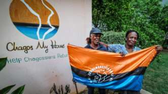 People hold a Chagos flag in front of a campaign banner | Photo: News Licensing / MEGA / Newscom/NEWSUK/Newscom
