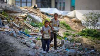 A photo of two small children carrying rubble through a bombed area | Saeed Jaras/MEI/SIPA/Newscom