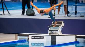 German swimmer Marius Kusch dives into a pool with his arms spread wide, with the logo for the company Enhanced displayed on the pool wall. | Photo: Maximilian Haupt/dpa/picture-alliance/Newscom