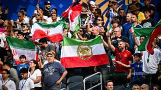 Soccer fans in a stadium holding up various versions of the Iran flag. | Brent Clark/Cal Sport Media/Newscom