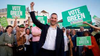 Green Party of England and Wales leader Zack Polanski holds his fist in the air in front of a crowd of supporters. | FIN/Capital Pictures / MEGA / Newscom/UCGBR/Newscom