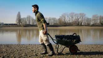 A volunteer pulls a cart as he helps clean the River Thames. | Stephen Simpson/Photoshot/Newscom