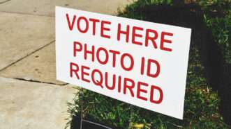 A sign at a polling place saying, "Vote Here. Photo ID required." | MargJohnsonVA/Envato